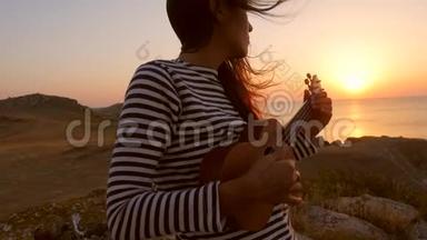 水手嬉皮白种人女孩演奏四弦琴吉他在美丽的日落附近的<strong>海洋</strong>。 <strong>高清</strong>慢镜头。